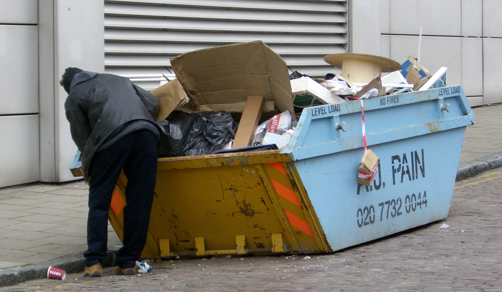 Immagine di un barbone che fruga nel'immondizia: Tecnica Dumpster Diving